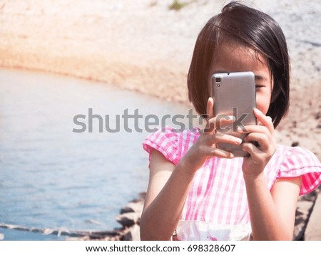 White shirt girl pink Playing phone at the waterfront online, taking pictures, chatting happily, having fun