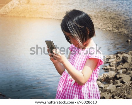 White shirt girl pink Playing phone at the waterfront online, taking pictures, chatting happily, having fun