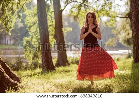 Attractive young female is practicing yoga and doing asana Vrikshasana in the morning.