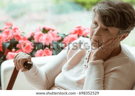 Sad elder lady sitting on the sofa and worrying about her health Royalty-Free Stock Photo #698352529