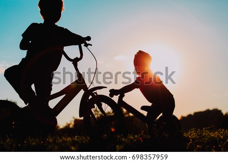 little boy and girl riding bikes at sunset