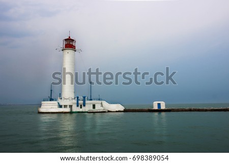White lighthouse with a red tip in the sea.