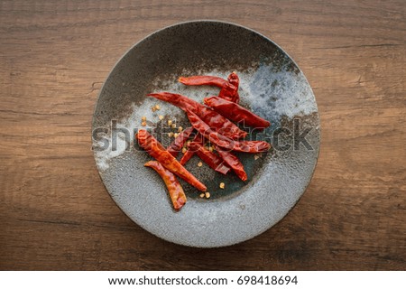Thai Dry chillies in old black ceramic Japanese dish on wood table