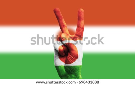 Niger national flag painted onto a male hand showing a victory, peace, strength sign