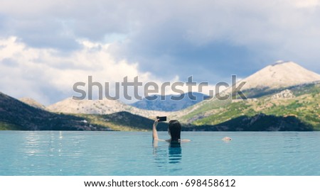 Young female in the pool on the roof in the background of the Greek mountains. Female in the swimming pool on the roof
