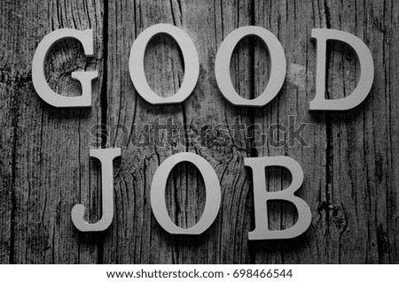 Wooden letters forming phrase GOOD JOB (uppercase) written on wooden background 