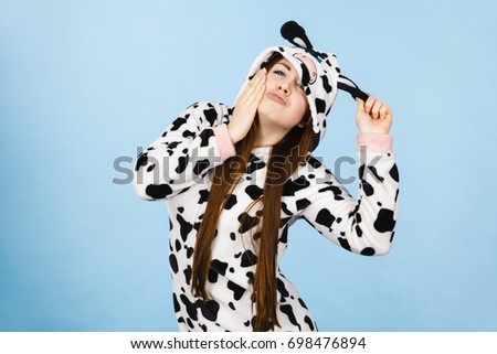 Happy teenage girl in funny nightclothes, pajamas cartoon style making silly face, positive face expression, studio shot on blue.