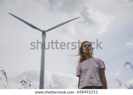 girl on a windmill background, summer windmills, sunset. Wind turbine, wind power. wind power plant