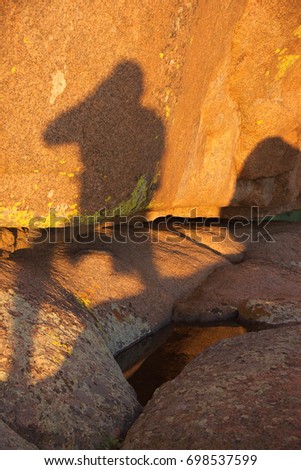 The silhouette of a photographer against red granite.  