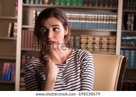 Young caucasian woman dressed like Jackie Kennedy poses in a library
