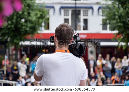 Back of professional young camera man camcorder outdoor in the city, filming People in Arendal week, in Arendal, Norway. 