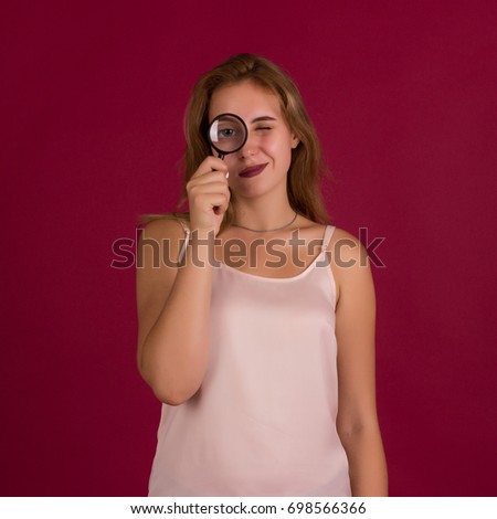 Young pretty girl with magnifier, studio