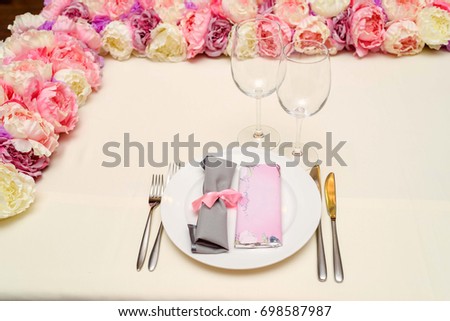 Rolled gray table napkin tied with pink ribbon and bar of chocolate with blank space for text on white empty plate on table. Table setting, free space. Table served for wedding banquet, close up view