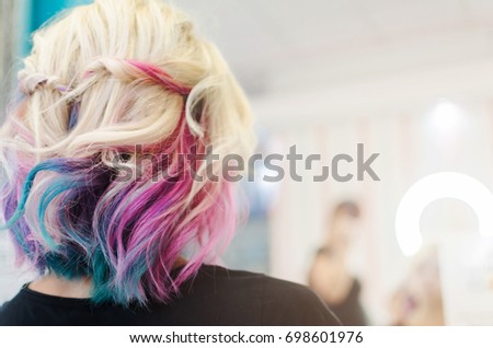 Happy woman in beauty salon with new hairstyle and haircut rainbow or unicorn hair.
