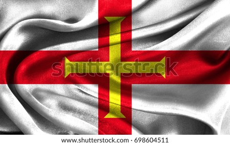Realistic flag of Guernsey on the wavy surface of fabric. This flag can be used in design
