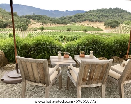 Table for two overlooking Napa Valley Wine Country vineyards. Two wooden chairs with two small wooden tables with carafes facing vineyards