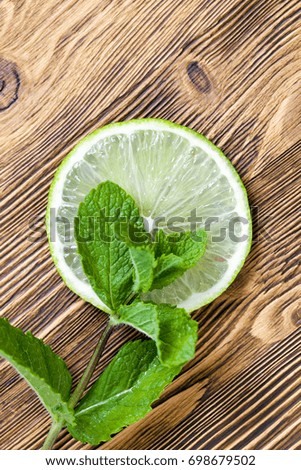 A fresh slice of green lime, photographed with leaves of fragrant mint. Photo close-up.