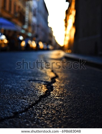Colorful closeup of weathered street with blurred lights and buildings in background - Florence, Italy