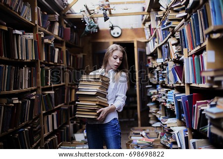 Lifestyle portrait of a lovely student girl wearing blue jeans and white shirt in vintage library or bookstore