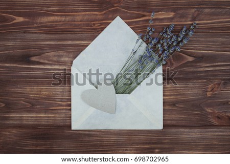Bouquet of lavender flowers and heart in a paper envelope on a wooden brown background. romantic background