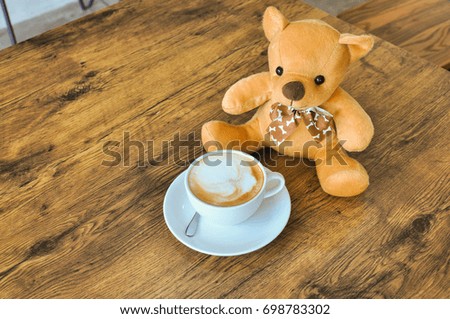 cup of coffee  on wooden table with teddy bear