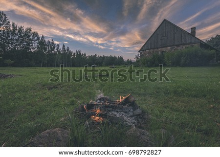 dramatic sunset over countryside in summer with house and fire place - vintage film look