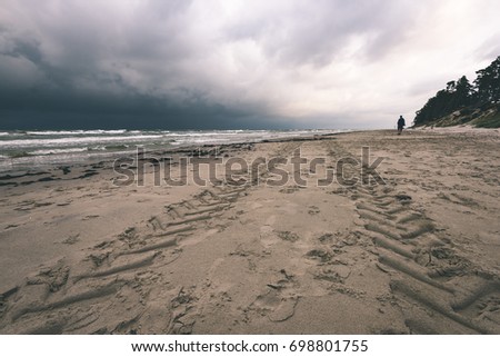 View of a stormy coast beach in the morning with lonely trees. Latvia, Liepaja. sun rays through the dramatic clouds - vintage film look
