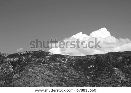 Black and white photo of huge puffy white monsoon clouds framing the Catalina mountains on a sunny day in the tucson arizona desert 