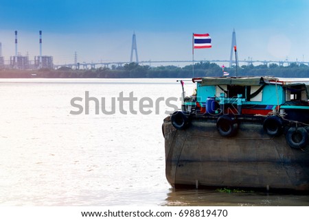 Back of an old cargo ship, the backdrop is a suspension bridge and a factory, Thailand