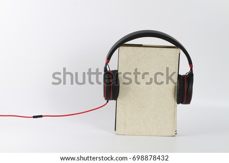 Headphone attached to a book over white background