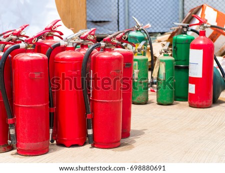 A lot of red fire extinguishers outdoors. Close up of many extinguishers fire available in fire emergencies on the ground. Concept of protection and security, safety first tools. - Selective focus.