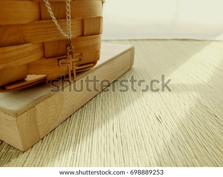 Christian Cross necklace on wooden background with morning sunlight