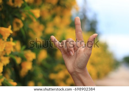 Hands are showing love symbol at flower background