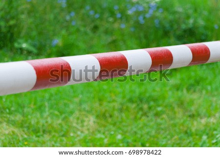 Metallic red white barrier on the road against a background of green grass
