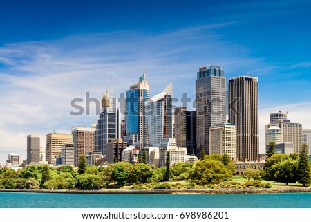Panoramic view at Sydney city skyscrapers from ferry with blue sky and clouds on a bright day