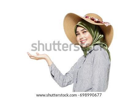 Pretty muslim woman wearing hijab use her hands sign towards show an empty space beside her, isolated on white background.