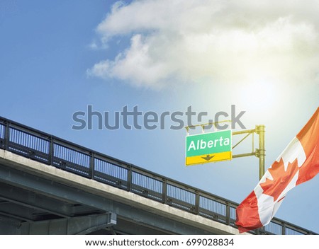 Destination province Alberta Canada sign on highway with Canadian flag waving beside