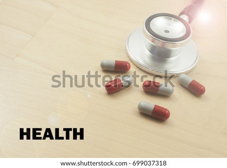 stethoscope,tablets pills capsule with word health concept isolated on wooden background