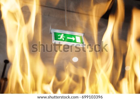 Low angle view of fire against emergency exit sign in building