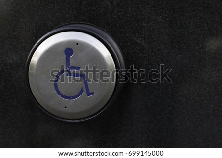 Handicap door button on a black wall