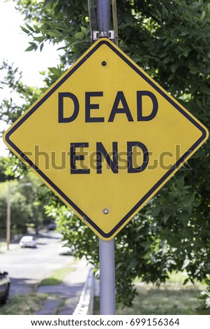 Dead end sign in front of a green street