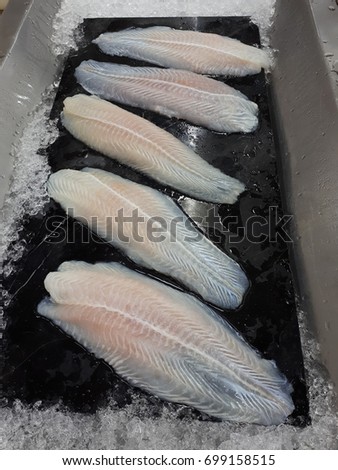 A large piece of white salmon is placed on a black tray that is ice-cold.