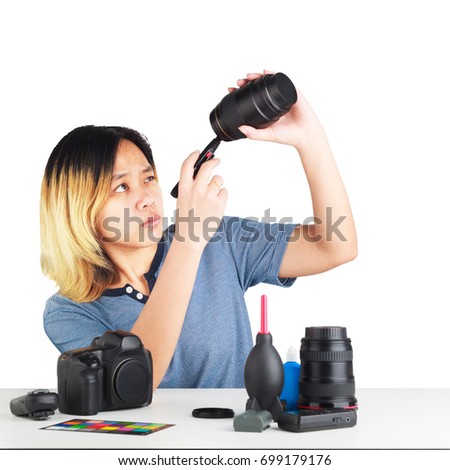 Asian woman maintenance a DSLR Camera with lens brush in her hand. Object is isolated on studio white background.