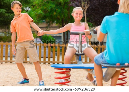 Children are teetering on the swing on the playground.