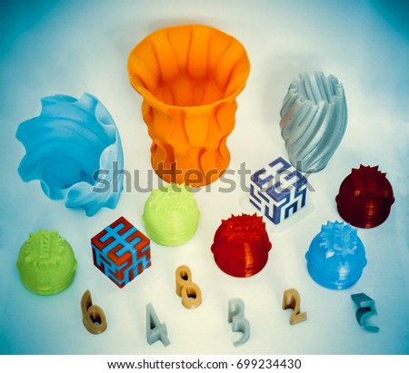 Models printed by 3d printer. Bright colorful objects printed on 3d printer on table.Automatic three dimensional printer performs plastic modeling in laboratory. Progressive modern additive technology Royalty-Free Stock Photo #699234430