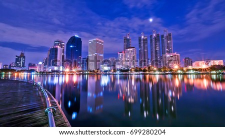 Night light cityscape view with modern building in the park beside lake at Bangkok, Thailand (Blue color tone)