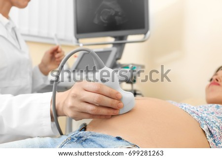 Young pregnant woman undergoing ultrasound scan in clinic Royalty-Free Stock Photo #699281263