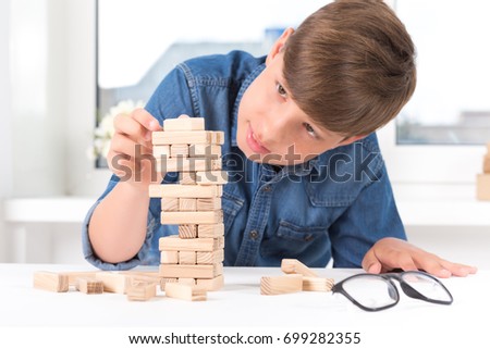 boy playing wood tower game on white table