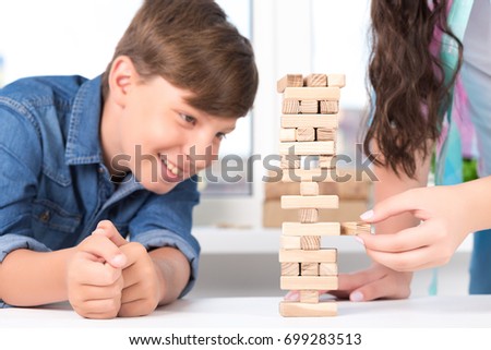 Boy and girl play wood tower game on white table