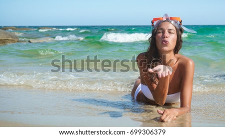 Beautiful young woman blowing a kiss, happy in a swimsuit wearing a diving mask.